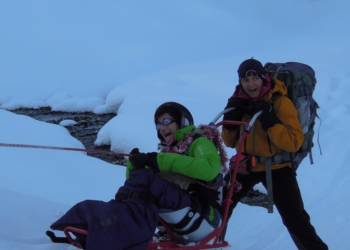 Descente en fauteuil-ski (dualski) à deux, activité montagne adaptée en hiver.
